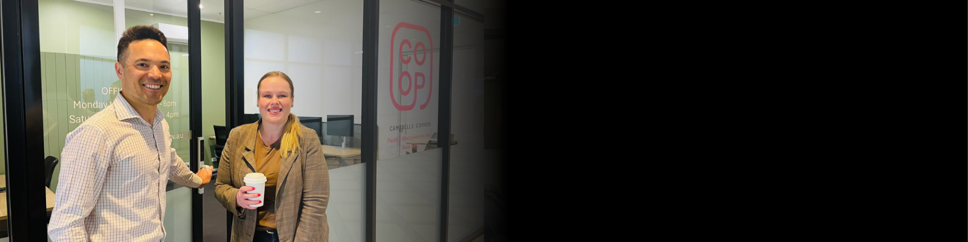 Two people smiling outside a shared office space